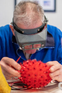 Een reparateur gebruikt een bril met speciale zoomglazen om beter te kijken naar een product.
