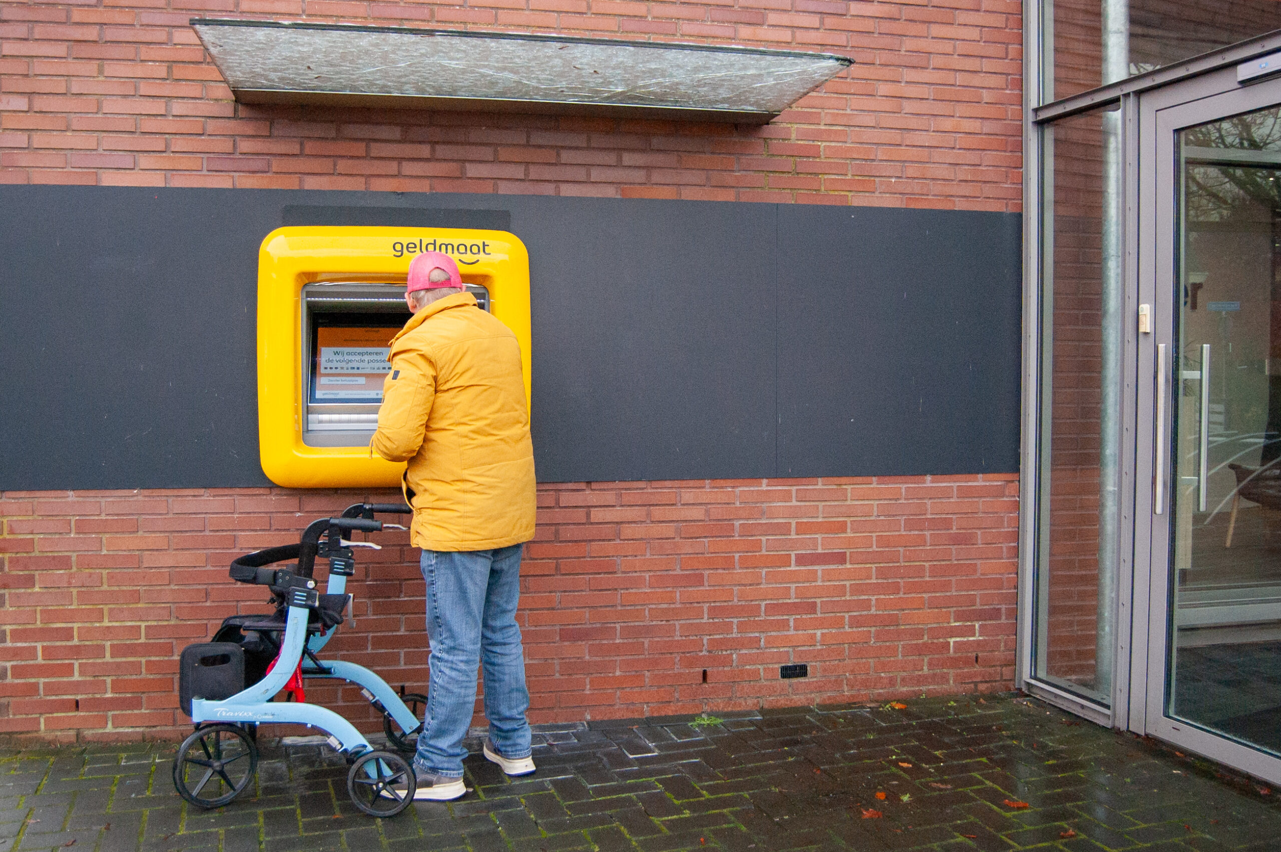 22/11/2024; Berjan Nieuwenhuis maakt een wandeling door het dorp Laren met zijn rollator, voorzien van een boerenzakdoek. Onderweg passeert hij het huis van zijn moeder, Jenny Nieuwenhuis. Berjan geniet van de wandeling en besluit even langs de pinautomaat te lopen om wat geld te pinnen voor een jarige die veel voor hem betekent.